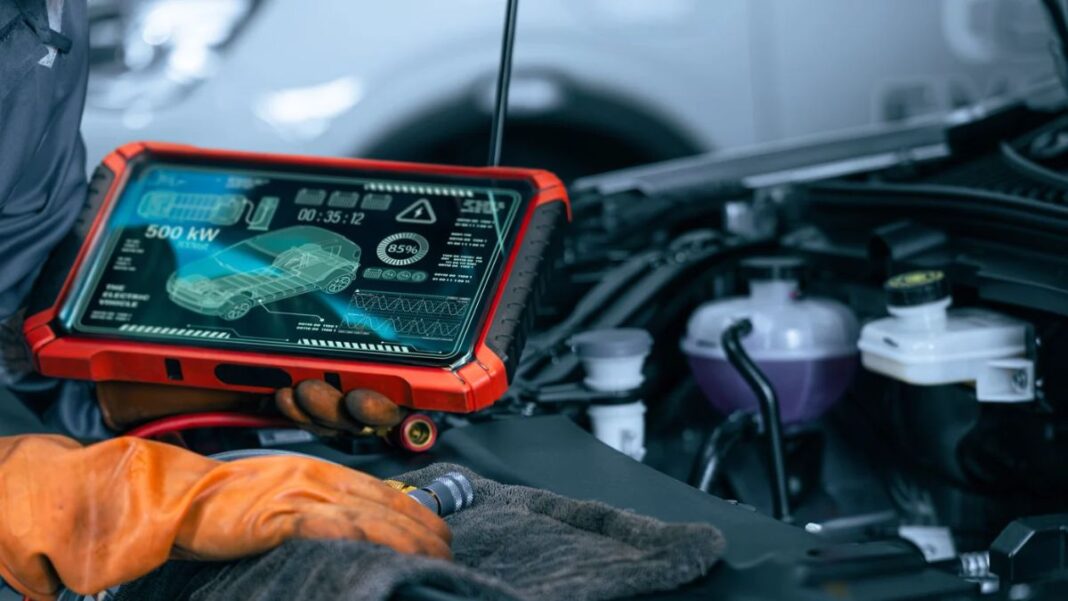 Técnico utilizando una máquina de diagnosis electrónica junto al motor de un vehículo.